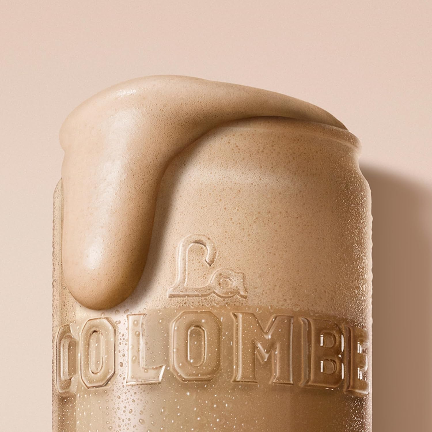 Close-up of a frothy glass of La Colombe Draft Latte 4 pack with creamy foam overflowing